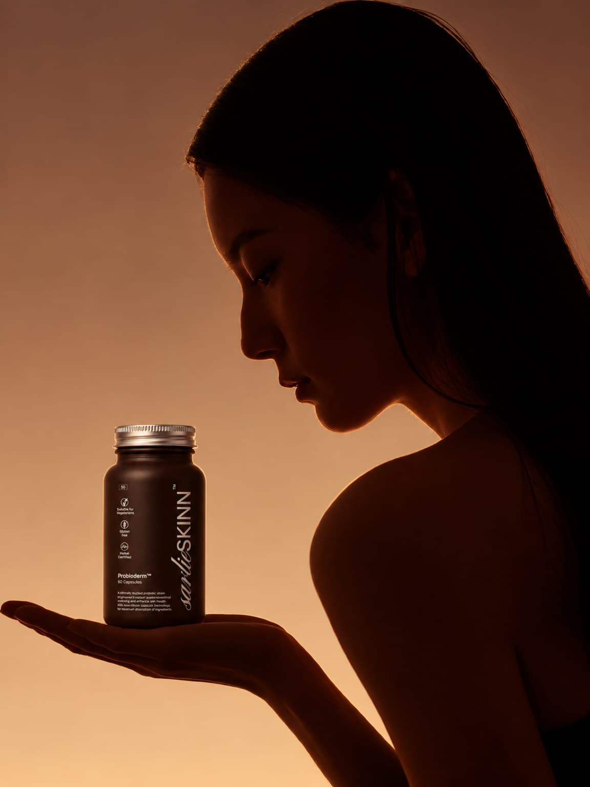 Silhouetted profile of a woman with a Probioderm bottle held in an open hand, amber light